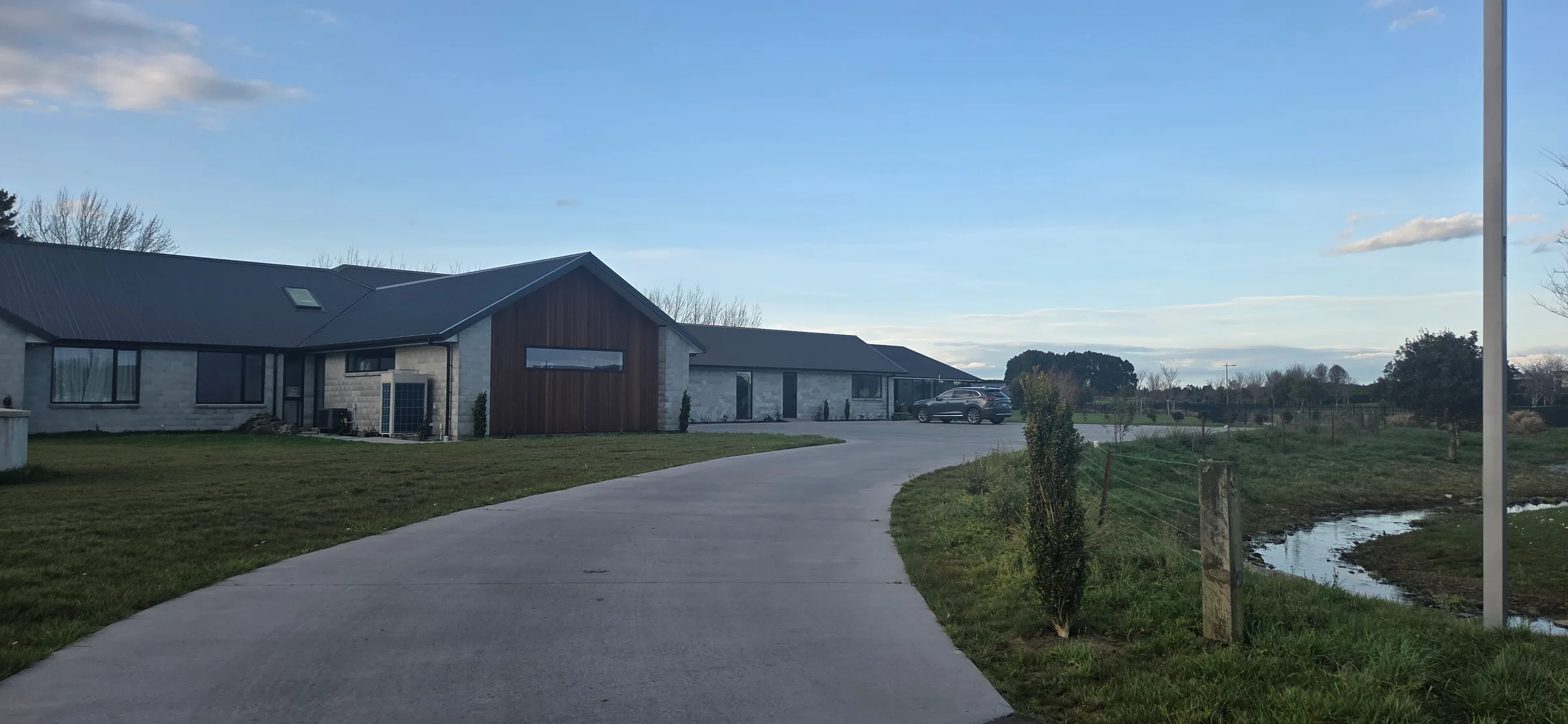 The house and driveway on a still evening, with paddocks beyond