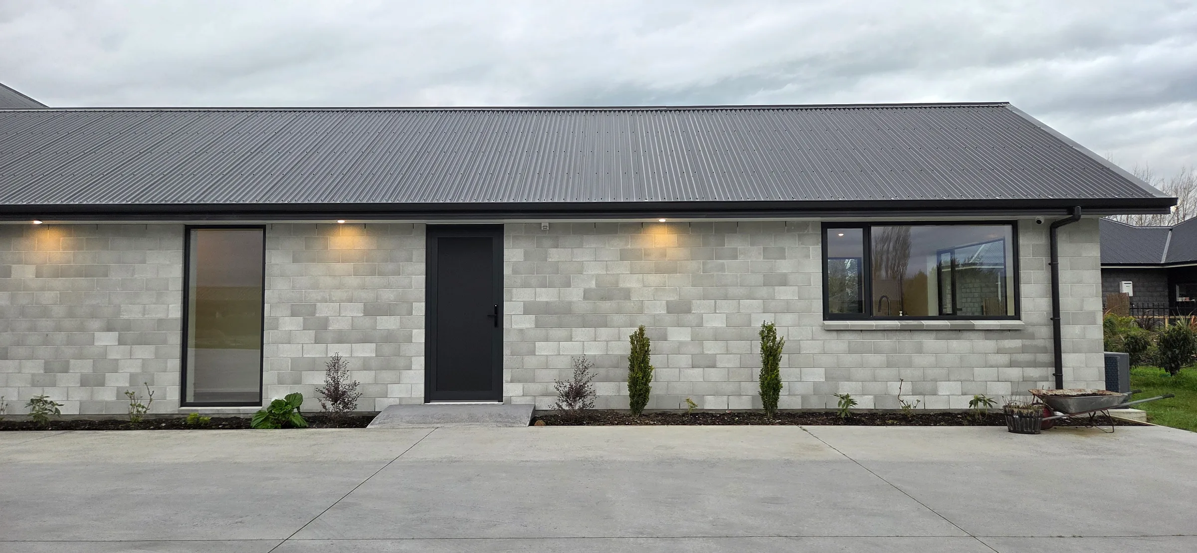 The guest flat from the driveway, with its own dark entry door set into pale block walls